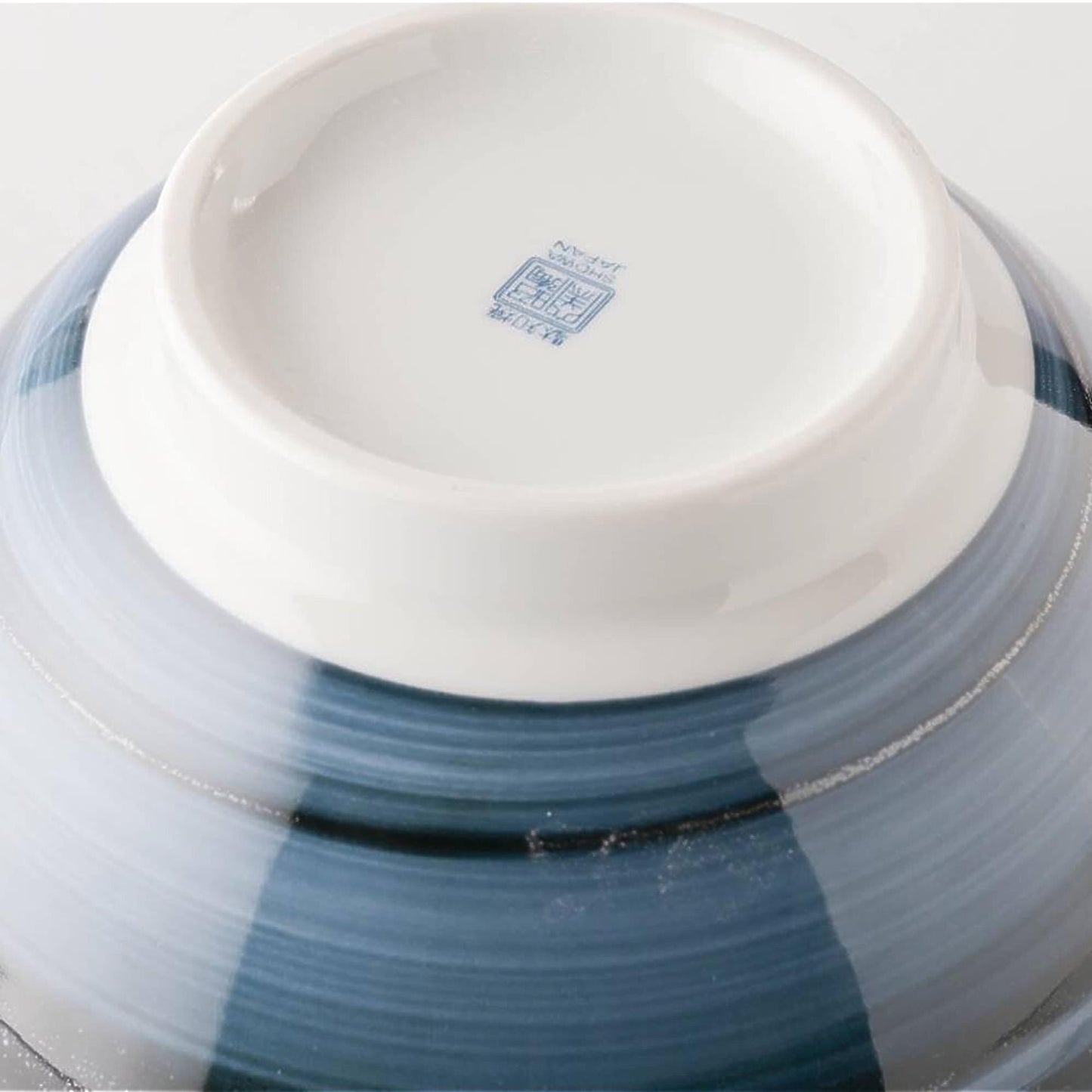 Ceramic bowl with blue and white glaze on a light gray background