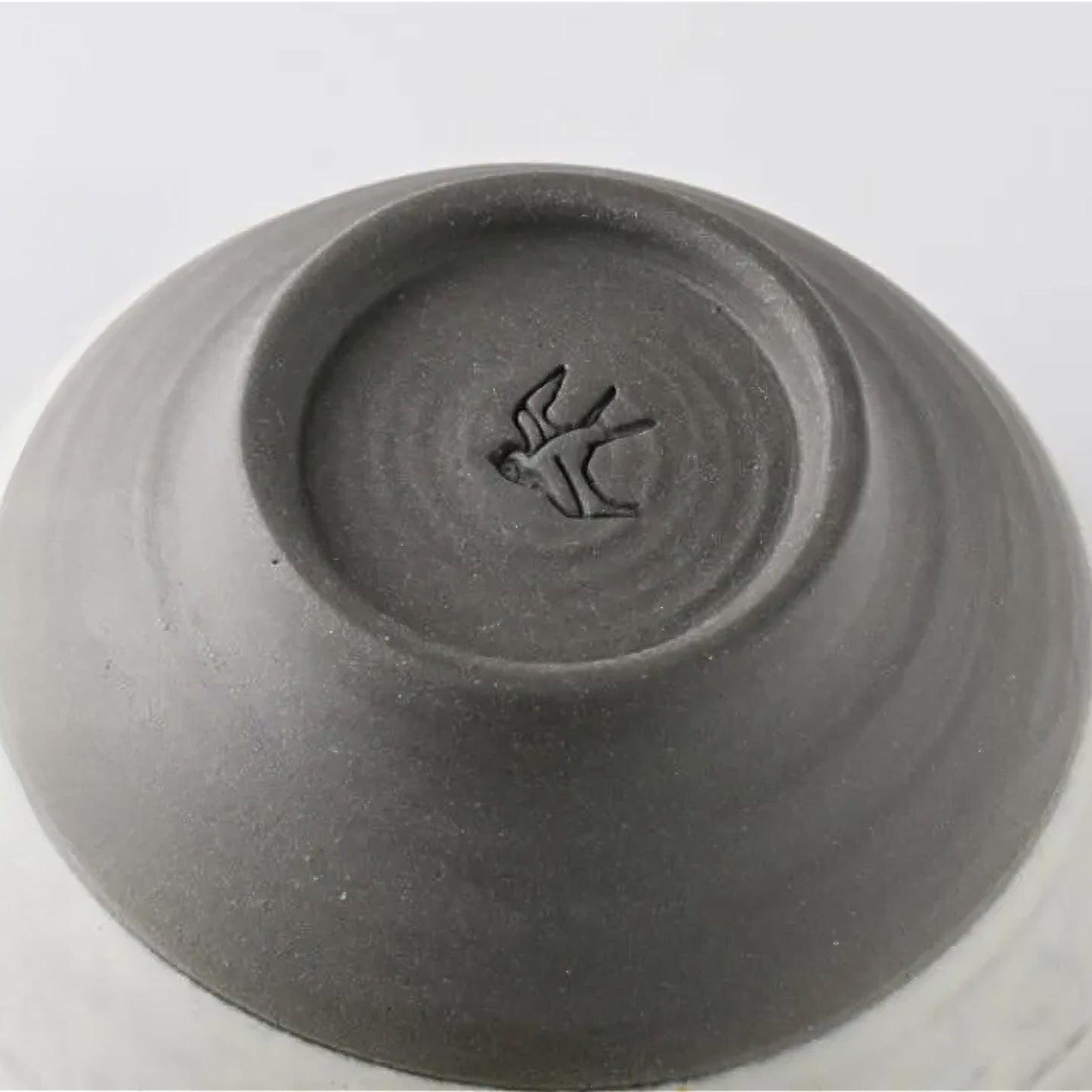 Gray ceramic bowl with a bird design on the bottom on a white background