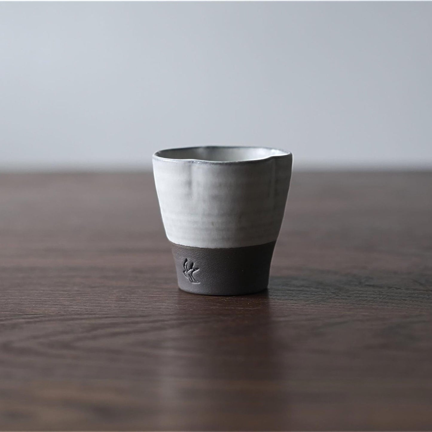 Ceramic cup with black base on a wooden surface