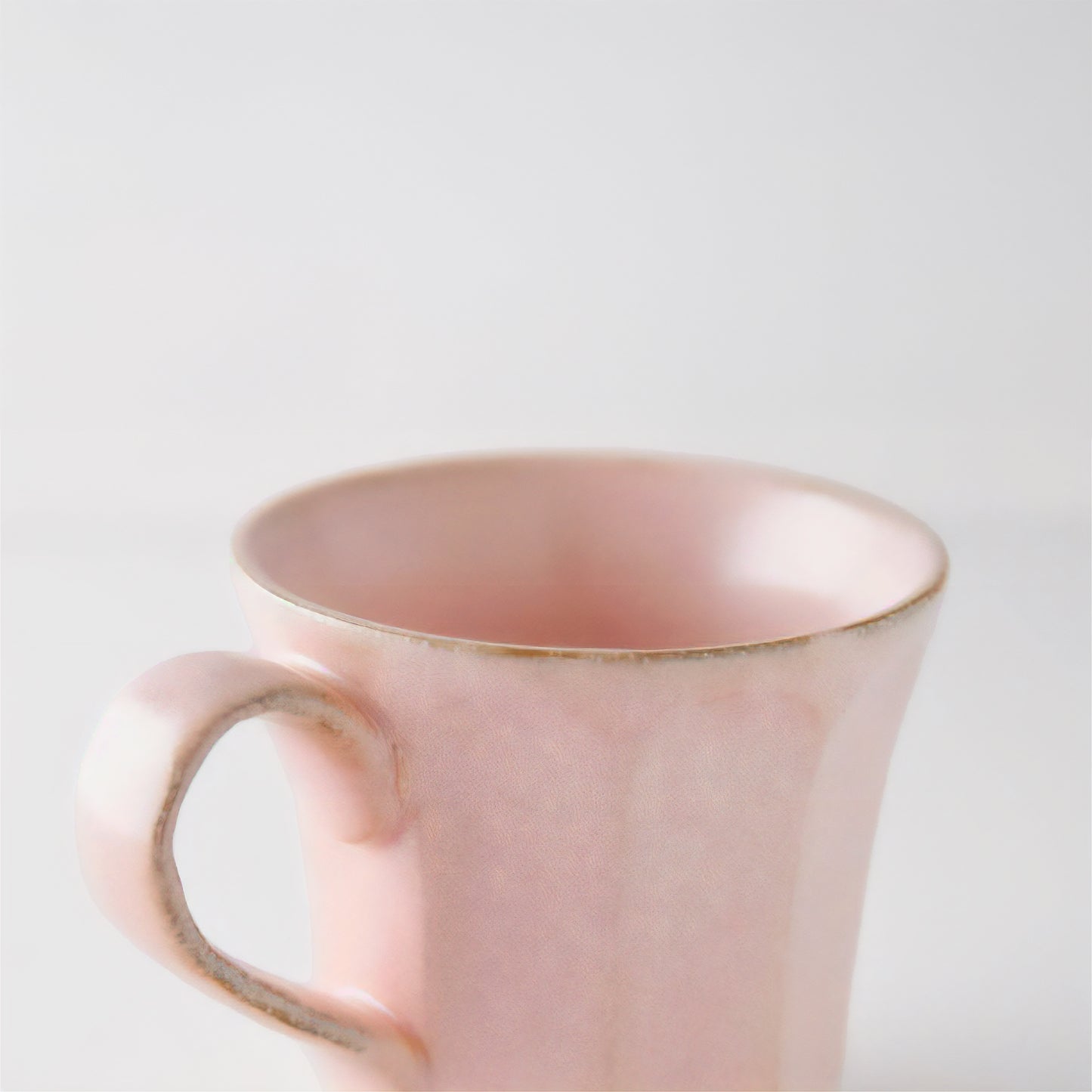 Pink mug with gold rim on a light gray background