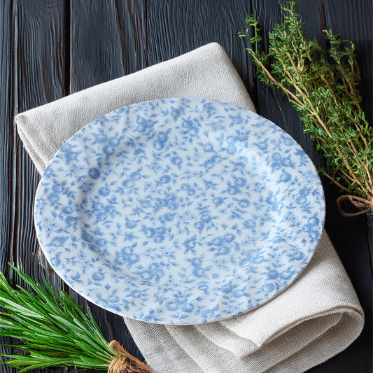 Blue floral-patterned plate on a white napkin with greenery on a dark wooden background