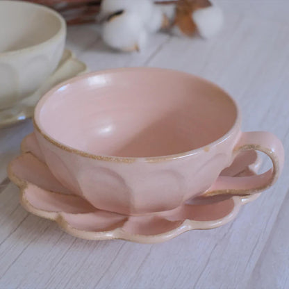 Pink ceramic cup and saucer on a light wooden surface