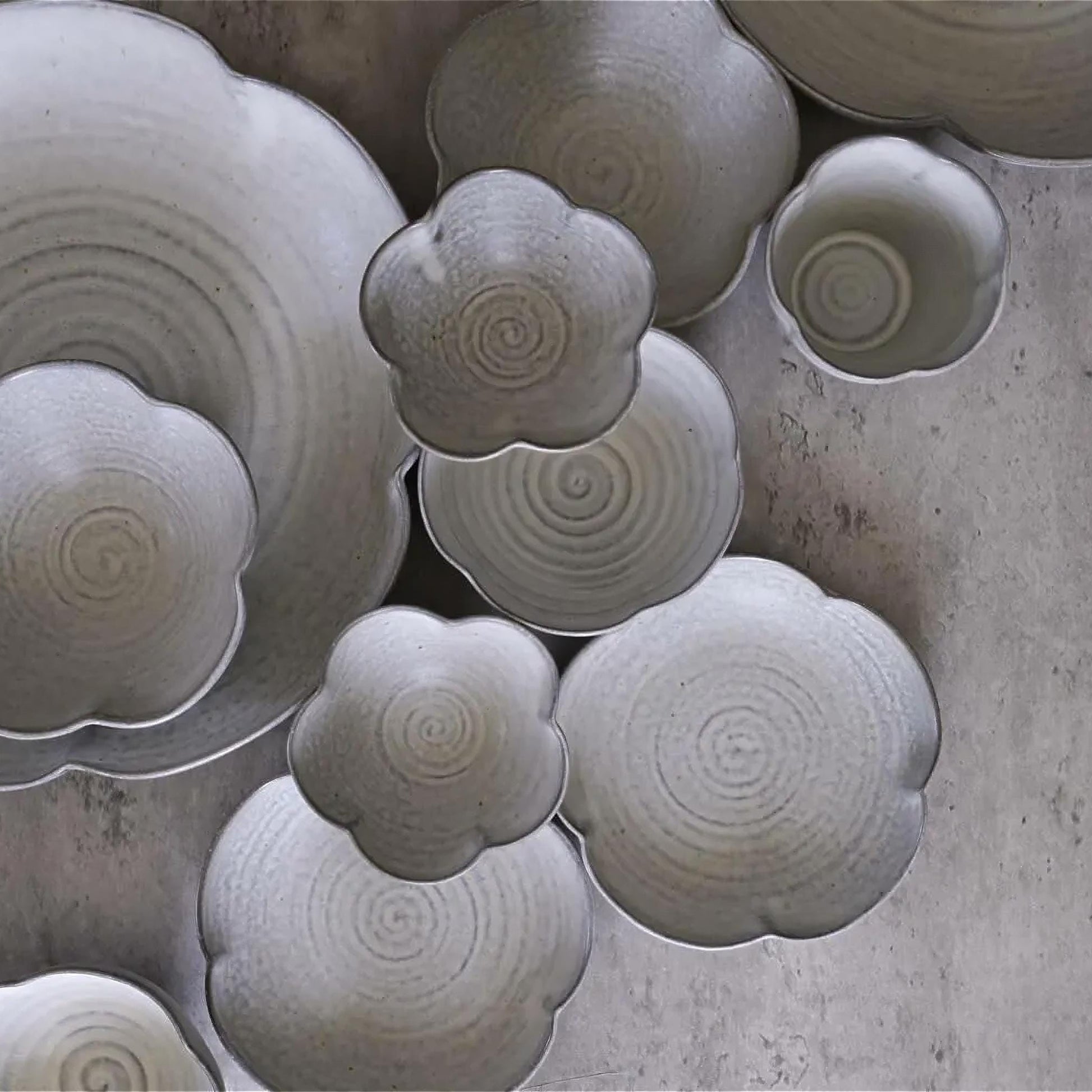 Collection of ceramic bowls with textured surfaces on a concrete surface