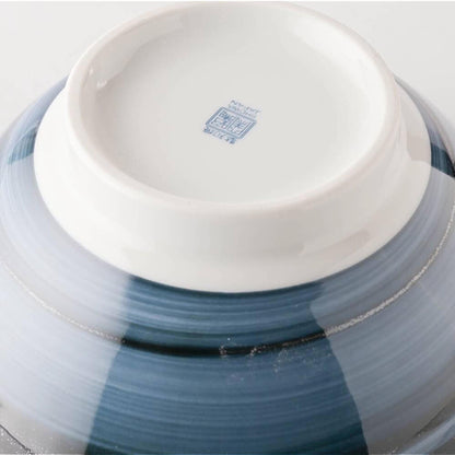 Ceramic bowl with blue and white glaze on a light gray background