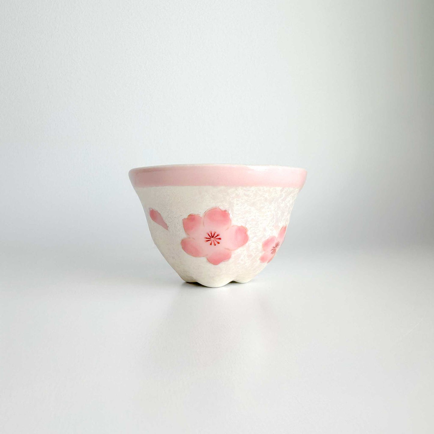 Ceramic cup and saucer with pink floral design on a white background