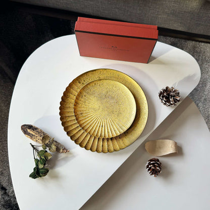 Decorative plates with a red box and natural elements on a white surface