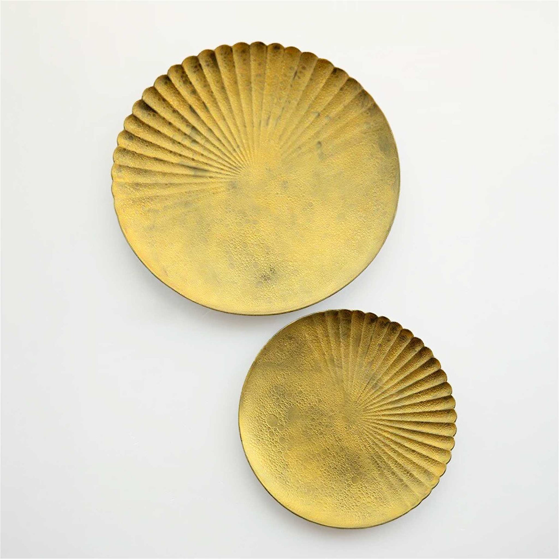 Two gold decorative plates with sunburst design on a white background