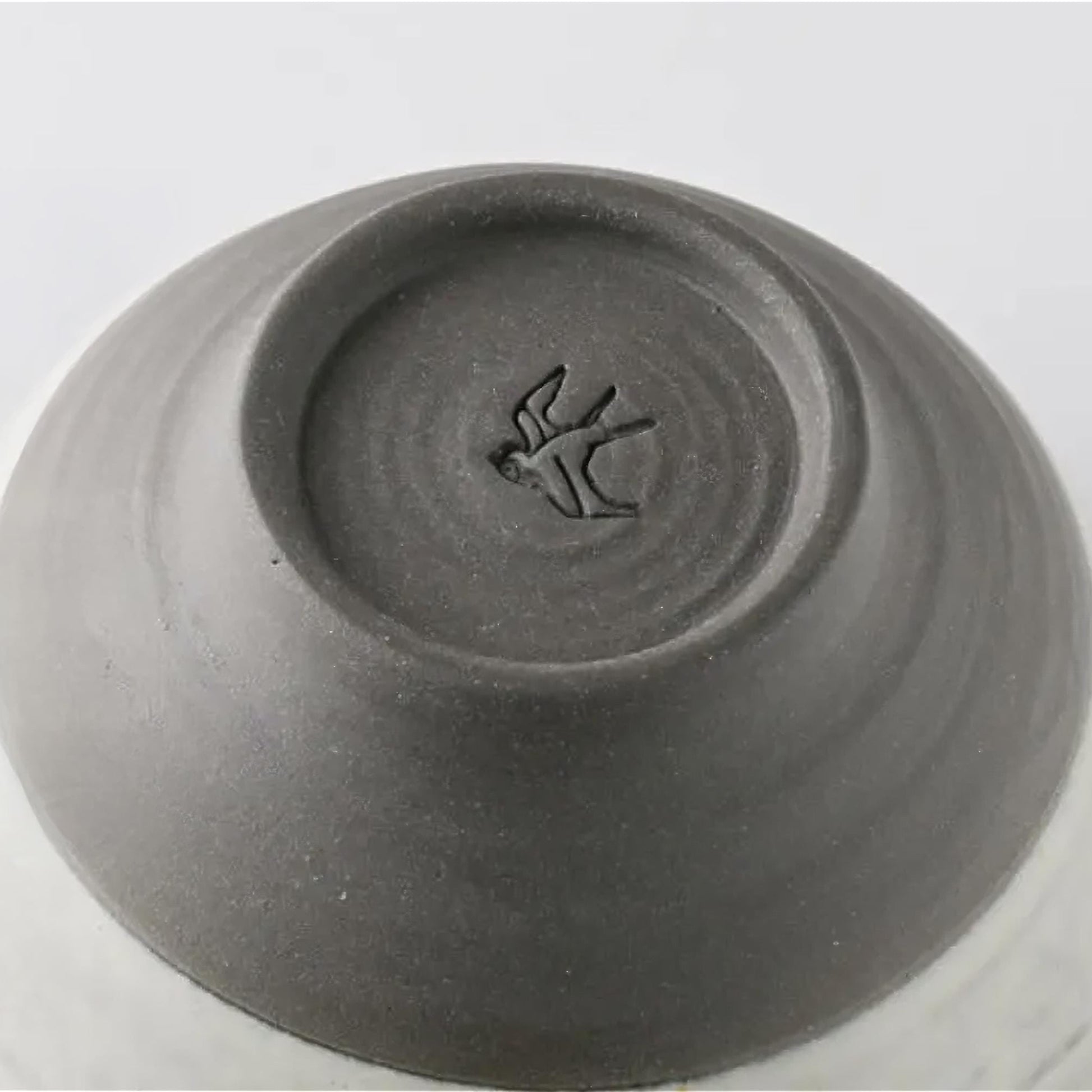 Gray ceramic bowl with a bird design on the bottom on a white background