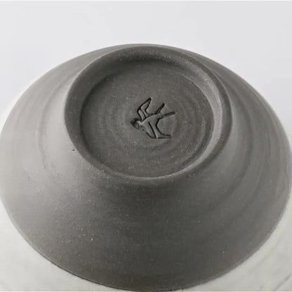 Gray ceramic bowl with a bird design on the bottom on a white background