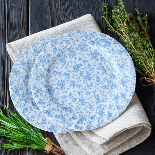 Two blue floral-patterned plates on a gray napkin with green herbs on a dark wooden surface.