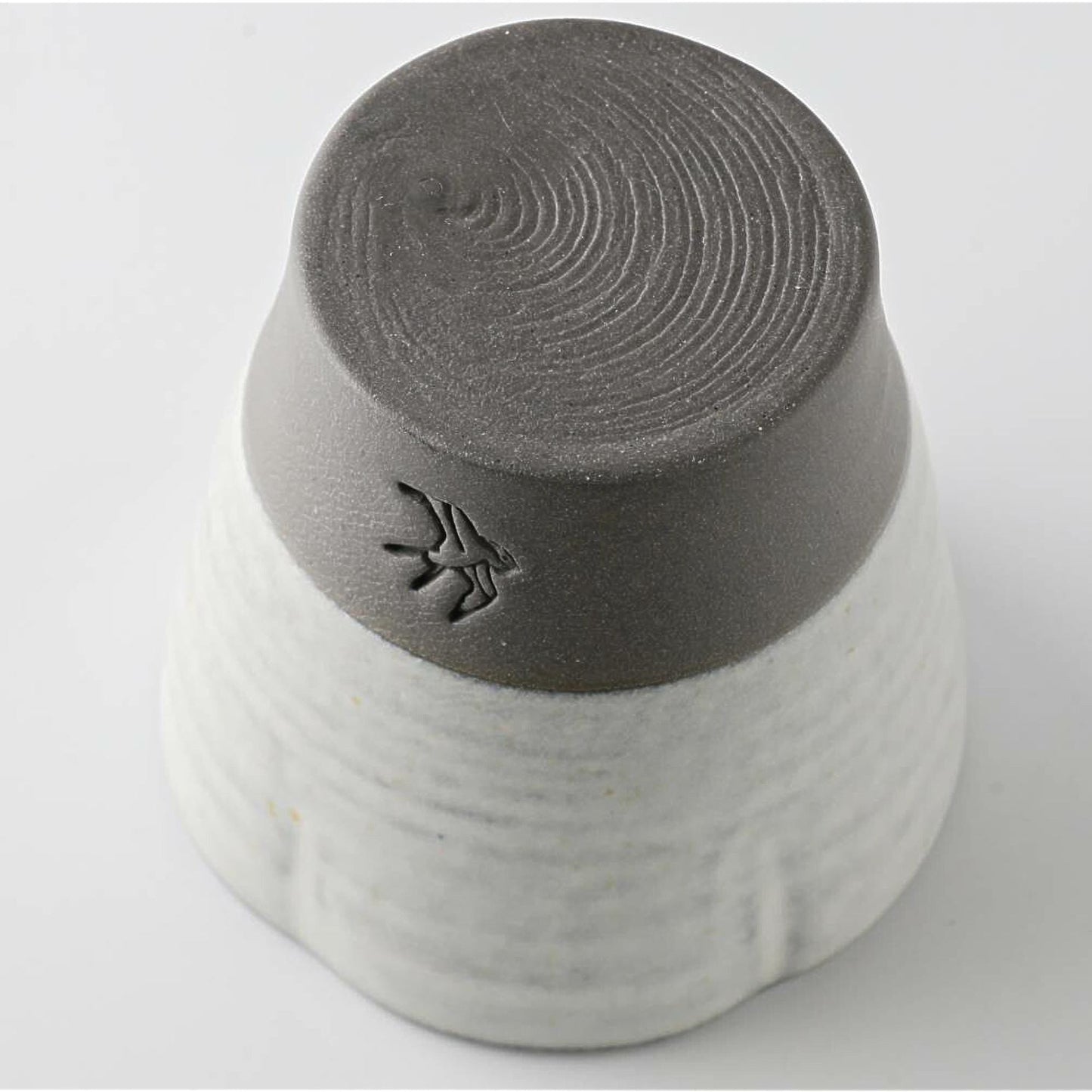 Gray and white ceramic cup with textured bottom on a light gray background