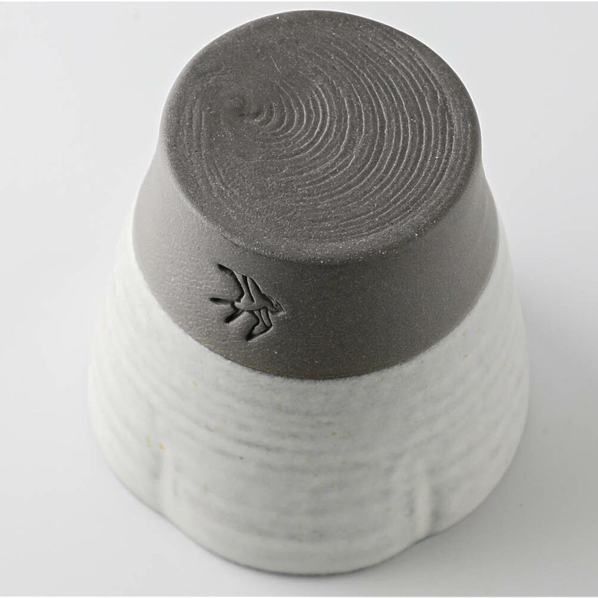 Gray and white ceramic cup with textured bottom on a light gray background