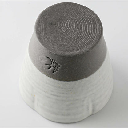 Gray and white ceramic cup with textured bottom on a light gray background