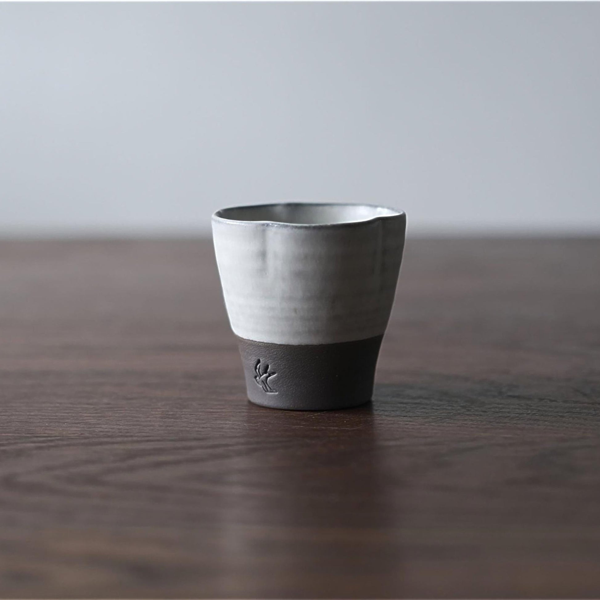 Ceramic cup with black base on a wooden surface