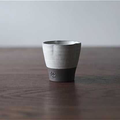 Ceramic cup with black base on a wooden surface