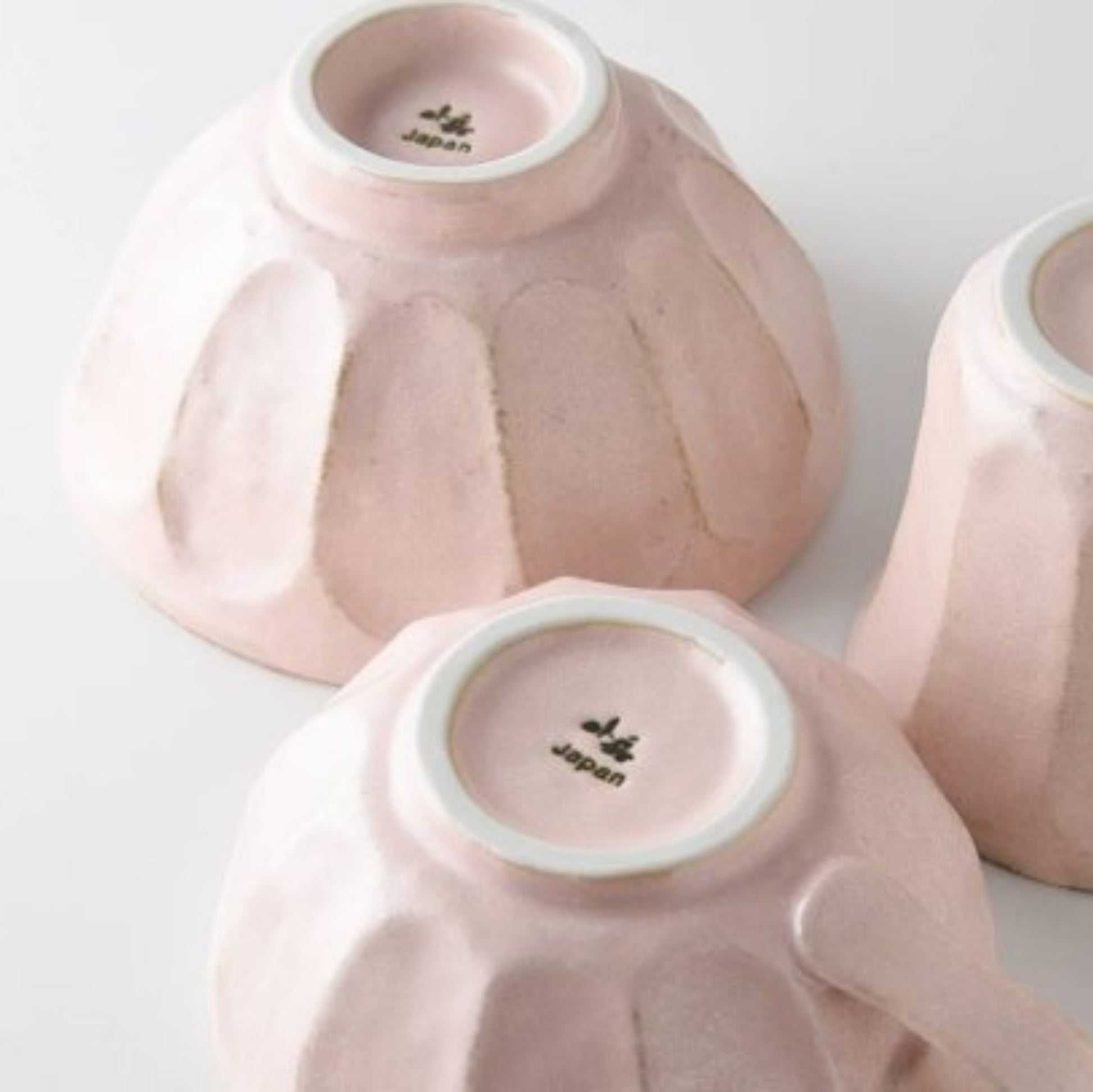 Three pink ceramic items with 'Japan' branding on a light gray background