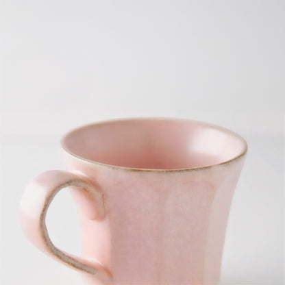 Pink mug with gold rim on a light gray background