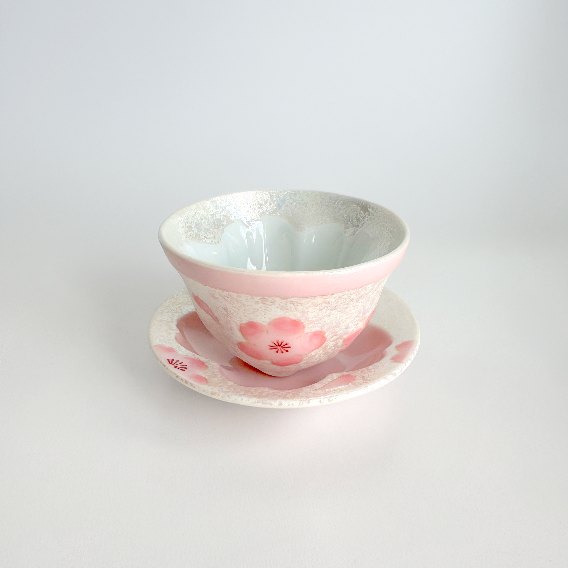 Ceramic cup and saucer with pink floral design on a white background