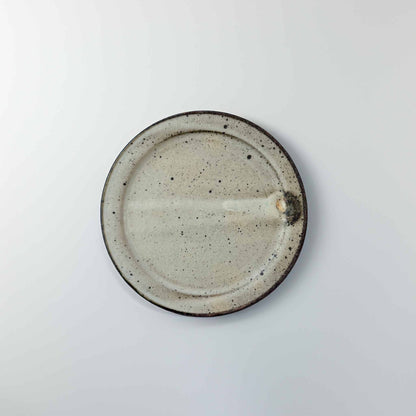 Round ceramic plate with speckled texture on a light gray background