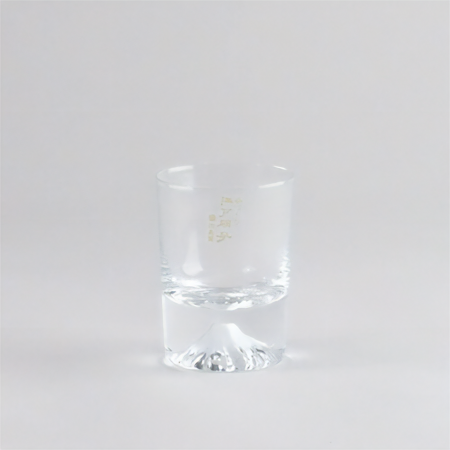 Clear glass tumbler with a gold logo on a white background