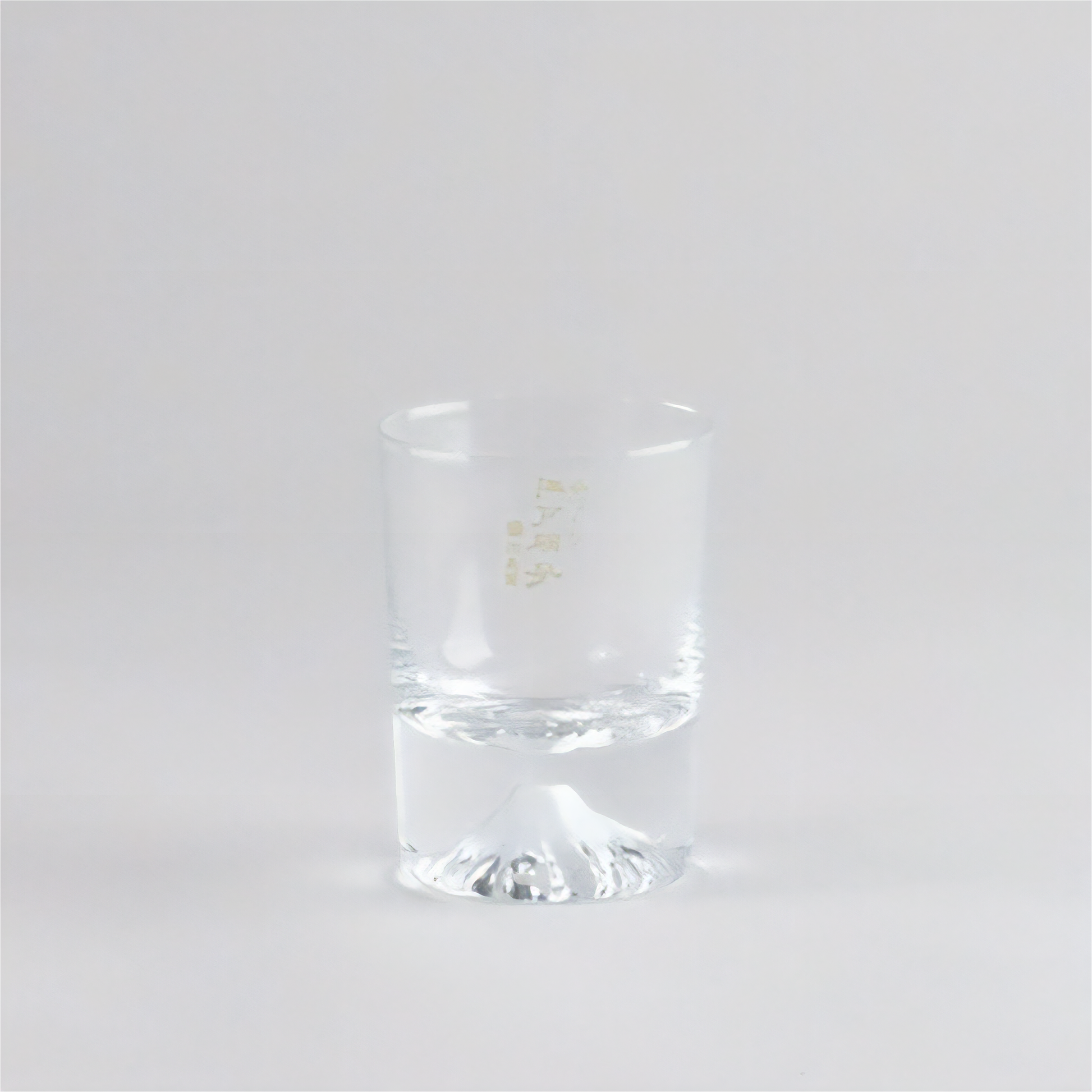 Clear glass tumbler with a gold logo on a white background