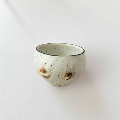 A small, handcrafted white ceramic soup cup with a natural glaze and subtle textures, set against a plain white background.