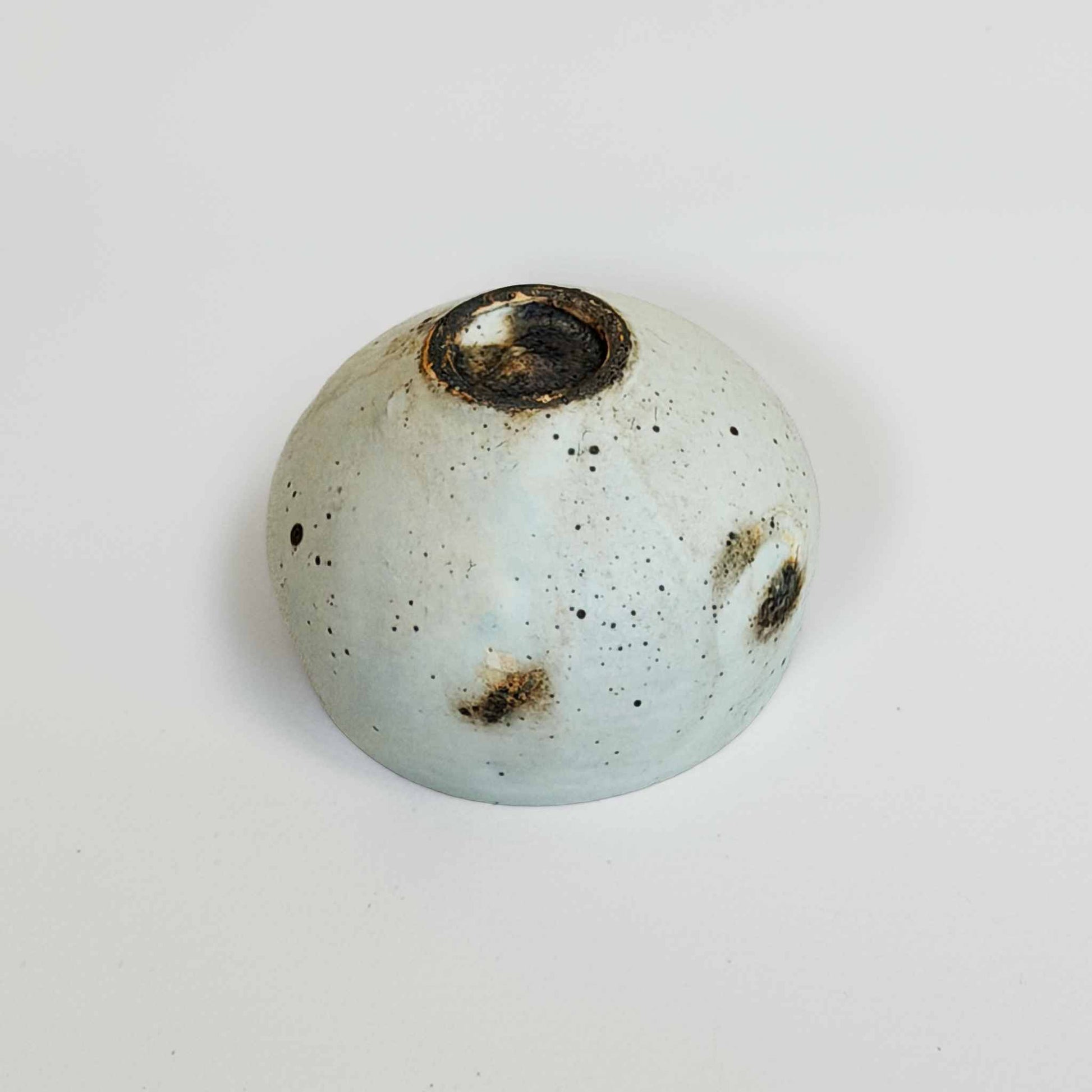 A small, white, handcrafted ceramic soup cup with a natural, speckled glaze, set against a plain white background.