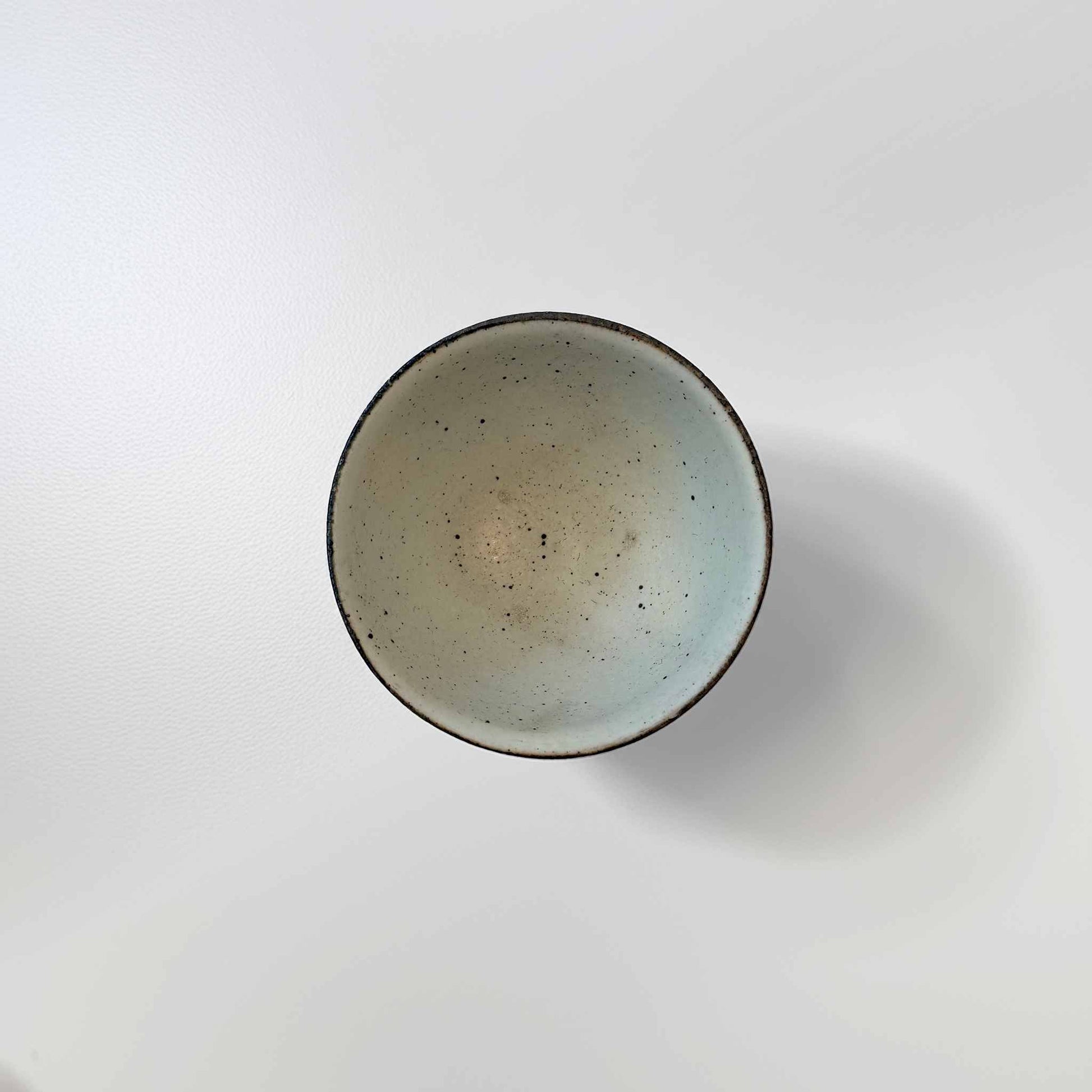 A small, handcrafted ceramic bowl with a soft kohiki glaze, set against a white background.