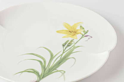 A white, scalloped-edged porcelain plate with a delicate, hand-painted yellow daisy design.