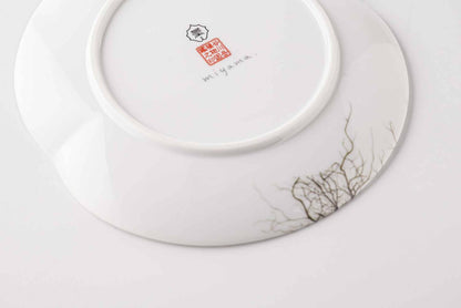 A delicate, white, ceramic plate with a botanical daisy design, set against a plain white background.