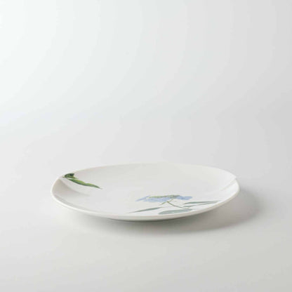 A white, hand-painted daisy on a small, white, porcelain plate.
