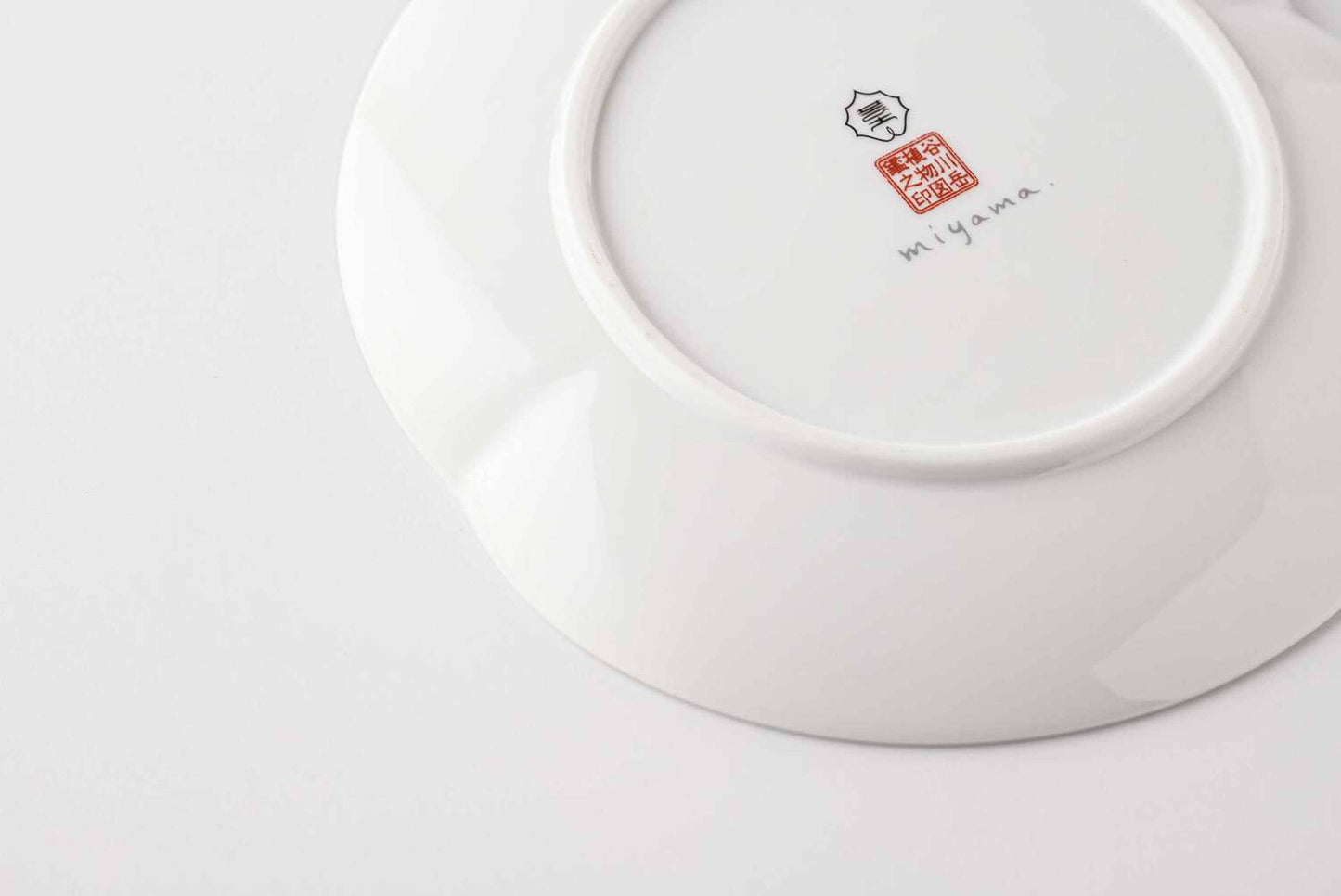 A white, delicate, and intricately designed 6-inch porcelain plate with a daisy pattern, made from Mino Ware, a type of Japanese porcelain.